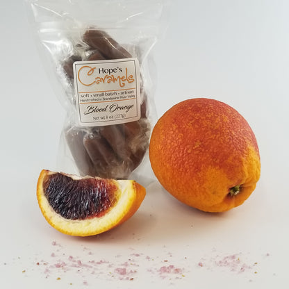 Blood Orange flavored caramel in clear bag behind a wedge and a whole blood orange